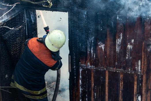 Firefighter work concept. Firefighter are using water in fire fighting operation. Real brave hero combat the fire with foam extinguisher. Brave firefighter saving burning building