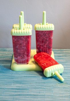 Homemade raspberry popsicles in a green mold during the summer heat.