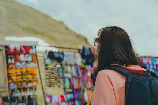 Woman tourist considering souvenirs in shopping booths.