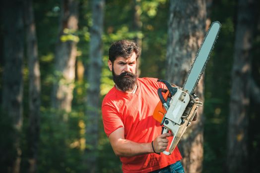 Deforestation is a major cause of land degradation and destabilization of natural ecosystems. Professional lumberjack holding chainsaw in the forest. Logging