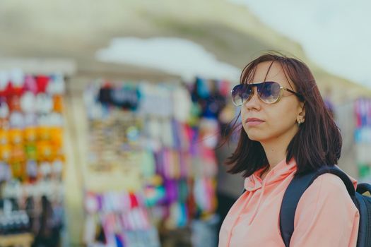 Woman tourist considering souvenirs in shopping booths.