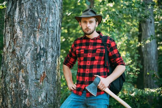 Handsome man with axe. Stylish young man posing like lumberjack. Deforestation is a major cause of land degradation and destabilization of natural ecosystems