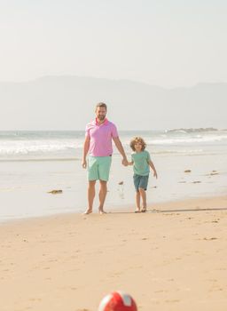 weekend family day. dad and child having fun outdoors. childhood and parenting. family holidays. sport activity. father and son play football on beach. daddy with kid boy on summer day.