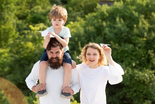 Portrait of happy father giving son piggyback ride on his shoulders and looking up. Summer ration. Happy family smiling and hugging. Happy family. Spring time