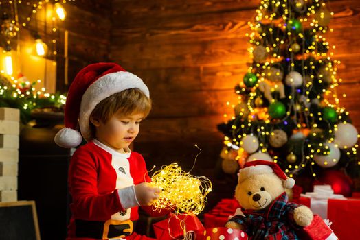 New year garland lights. Christmas time. Happy little child play with xmas decorations. Lovely baby enjoy christmas. Santa little helper. Helper of Santa with a Christmas magic gifts