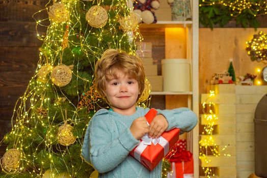 Winter kid. Christmas children. Child with gift. Winter Christmas emotion. Child with a Christmas present on wooden house background