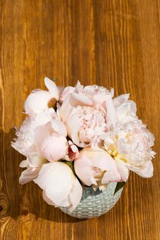 sunlit white peony flower in a bouquet and in a vase on the background of an old table, closeup