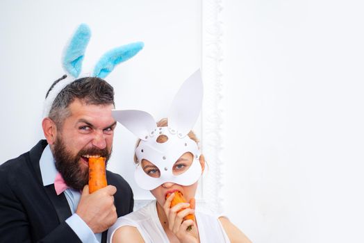 bearded man and sexy girl. copy space. Rabbits family with bunny ears. Holiday celebration, preparation. Easter bunny. happy easter. spring holiday. Egg hunt. easter bunny couple eat orange carrot.