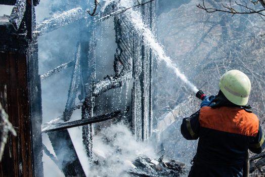 Real brave hero combat the fire with foam extinguisher. Strong and brave firefighter saving burning building. Firefighter work concept. Firefighter are using water in fire fighting operation