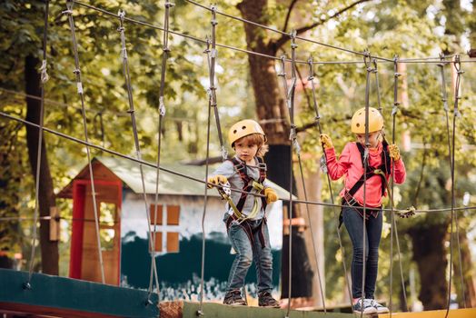 Rope park - climbing center. Carefree childhood. Happy Little girl and boy climbing a tree. Adventure climbing high wire park. Hike and kids concept