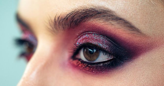 Professional smokey eyes make up at beautiful girl for special occasion. Shiny glitter pigments in eyes make up. Luxury eye makeup concept. Purple smokey eyes makeup close up photo