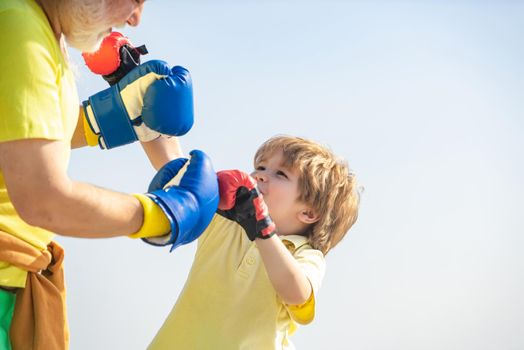 Funny bearded man - grandfather with child boy standing in boxing pose. Fighter. Handsome elderly man practicing boxing kicks