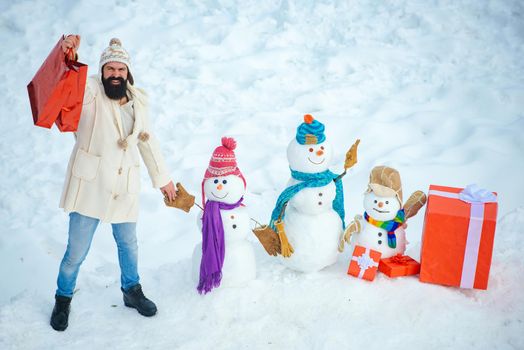 Happy father playing with a snowman on a snowy winter walk. Christmas banner. Hipster Santa Claus