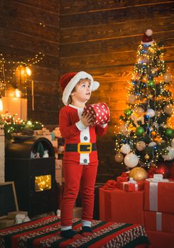 Bright New Years interior. Boy cute child cheerful mood play near Christmas tree. Indoor. Joy and happiness. Christmas shopping concept. Holidays and winter childhood concept