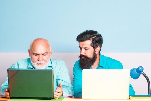 A grandfather and a son are learning in class. Old and Young. Concept of a retirement age. Portrait of confident old male teacher