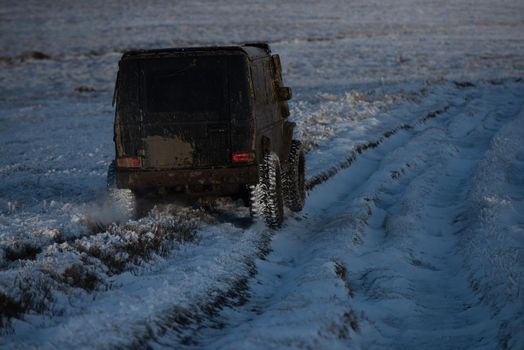 4x4 Off-road suv car. Wheel close up in a countryside landscape with a muddy road. Off-road vehicle goes on the mountain. Safari. Adventure travel. Expedition offroader