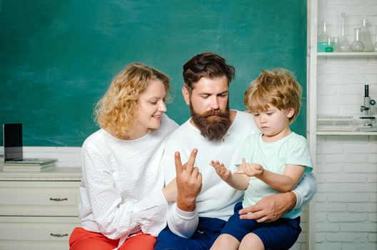 Counting on fingers. Young couple helping his son to make homework. Education for children out of school. Kids at preschool. Child from elementary school with parents in school. Education