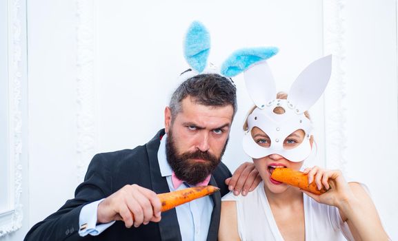 Respect traditions. Happy easter day. Bunny rabbit man and girl eat carrot. Cute bunny wear formal suit tuxedo. Celebrating easter. Office party celebration. Healthy snack. Easter coming. Have a bite.