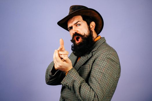 Bearded man holds imaginable gun in his hands and looks at the camera. Hand with fingers set into gun gesture. Symbolizing shooting someone