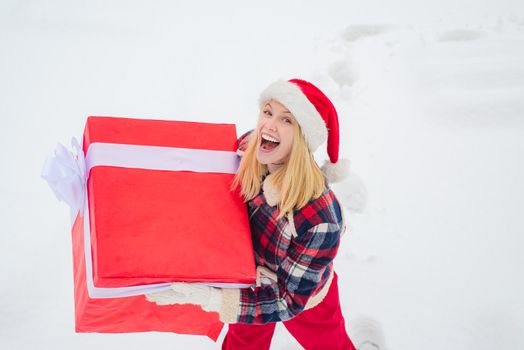 Service women with big gift box. Santa woman holds a big gift box with copy space for your text. Happy winter time. Woman carrying a big present isolated on snow winter background