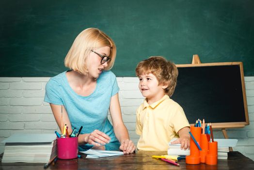 Elementary school - education and learning child concept. Teacher helping kids with their homework in classroom at school. Teachers day