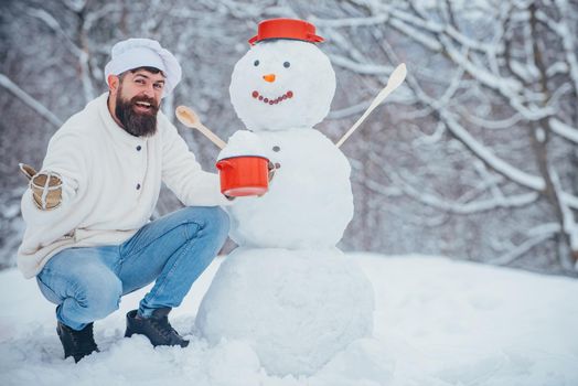 Funny Christmas chef cook. Christmas preparation - funny bearded man with snowman. Man is happy about the new year. Hipster Santa Claus