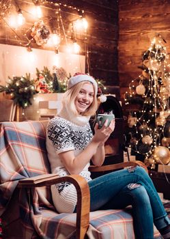 Beautiful cheerful girl with cup of tea or cofee. Cozy knitted sweater. Christmas miracle and new year feelings