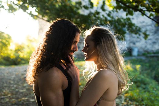Couple in love. Romantic feelings and tender love concept. Sensual woman touching face of her handsome boyfriend. Couple walking in the park. Beautiful couple in love standing close to each other