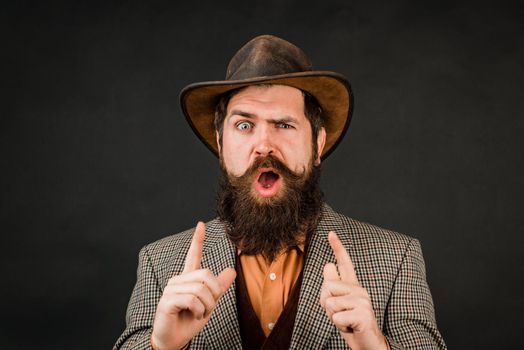 Funny brutal bearded hipster on isolated background. Close up photo of handsome funny man with beard in suit. Hand with fingers set into gun gesture