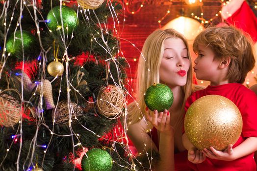 Cute Santa baby boy kissing his mum or sister. Bright New Years interior. Present box. Merry Christmas and New Year. Joy and happiness. Happy little child play with christmas decorations