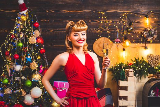 Colorful makeup and retro hairstyle for Christmas or new year party. Excited and happy. Beautiful pinup girl with Christmas holiday pin-up makeup holding glass of champagne