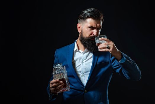 Luxury alcohol drink. Degustation of elite alcohol. Confident bearded man in black suit with glass of whisky in loft