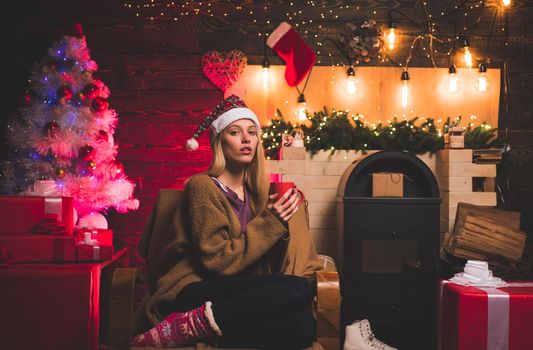 Fashion portrait of girl indoors with Christmas tree. Funny girl in Santa costume. Gift emotions. Emotions. Celebration. Christmas home atmosphere