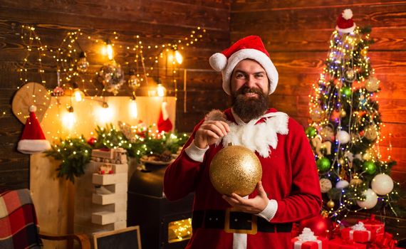Hipster man, bearded Santa celebrate Thanksgiving day and Christmas. Home Christmas atmosphere. Fashion portrait of handsome man indoors with Christmas tree