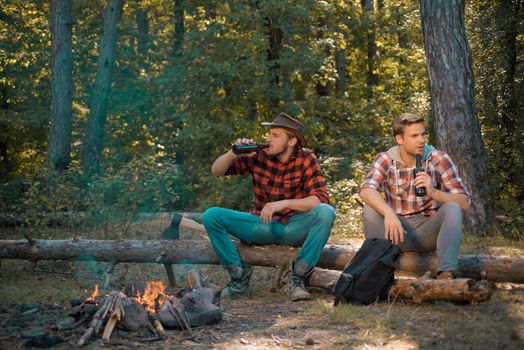 Friends having fun at camp fire. Young guy having a picnic. Young man having picnic in woods. Weekend. Friendship and leisure concept. Group of young people having fun outdoors