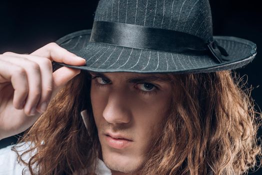 Young handsome man emotional pose with hat. Portrait of handsome young serious confident young guy with long hair in hat. Man with confident face and brutal style. Barbershop advertising