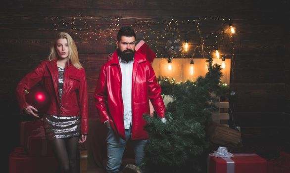 Christmas tree. Beautiful Couple dressed in a Santa hat. Handsome bearded hipster Santa with smiling positive young woman. Having a crazy day with friend