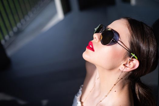 Portrait of a young woman in sunglasses. Close-up portrait of a beautiful charming young attractive lady. Young woman posing. Beautiful young model with big glasses-close up. Dark background