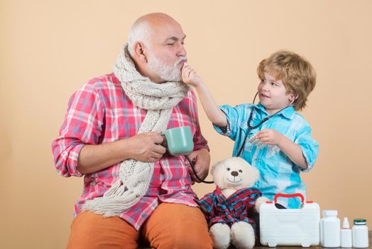 Family medicine concept. Parenting. Smiling grandfather and his grandson playing with a stethoscope. Healthcare profession people and medicine concept