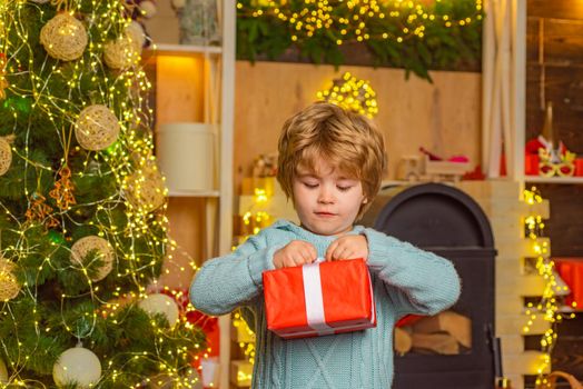 Cheerful cute child opening a Christmas present. Happy child decorating Christmas tree. Cute little child near Christmas tree