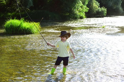 Child fishing. Kid learning how to fish holding a rod on a river. Little boy fisherman with fishing rod. Young man fly fishing