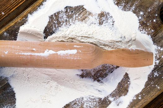 a wooden rolling pin and white wheat flour used during cooking baking at home