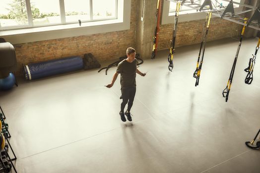 Full length of young sporty man is skipping rope while exercising at gym. Sport concept. Fitness. Active life