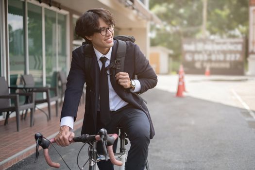 Handsome young asian businessman in suit have smiling with bicycle go to work at morning.soft focus.