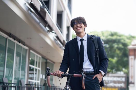 Handsome young asian businessman in suit have smiling with bicycle go to work at morning.