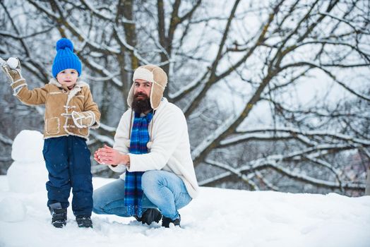 Happy father and son play on winter Christmas time. Fathers day. Happy child playing with snowball against white winter background. Happy loving family