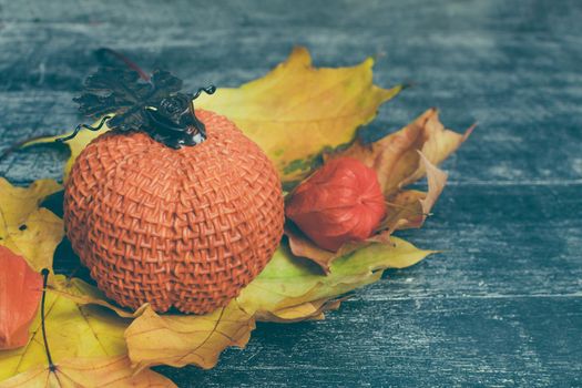 Autumn composition. Pumpkin, dried leaves and physalis on wooden background. Autumn, halloween concept.
