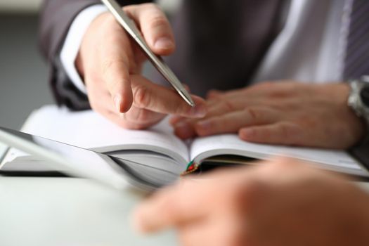 Hand of businessman in suit filling and signing with silver pen partnership agreement form clipped to pad closeup. Management training course some important document, team leader ambition concept