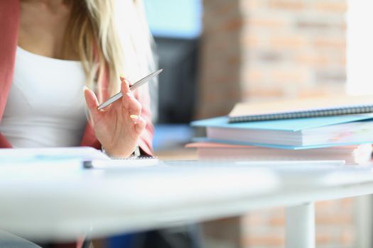 Business woman holding silver ballpoint pen at table with folders closeup. Paper work concept