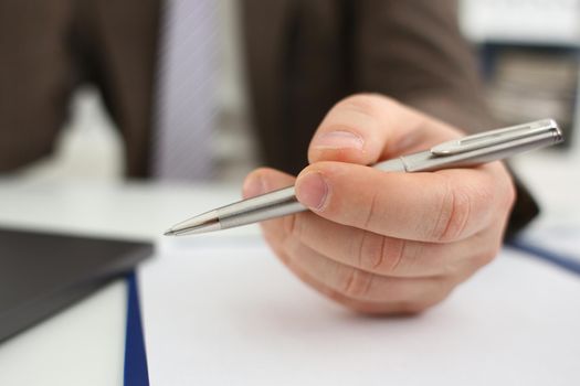 Male arm in suit and tie hold silver pen filling schedule in notepad at office workplace closeup. Legal law consult assistance gesture or finance investment advisor clerk job information gesture